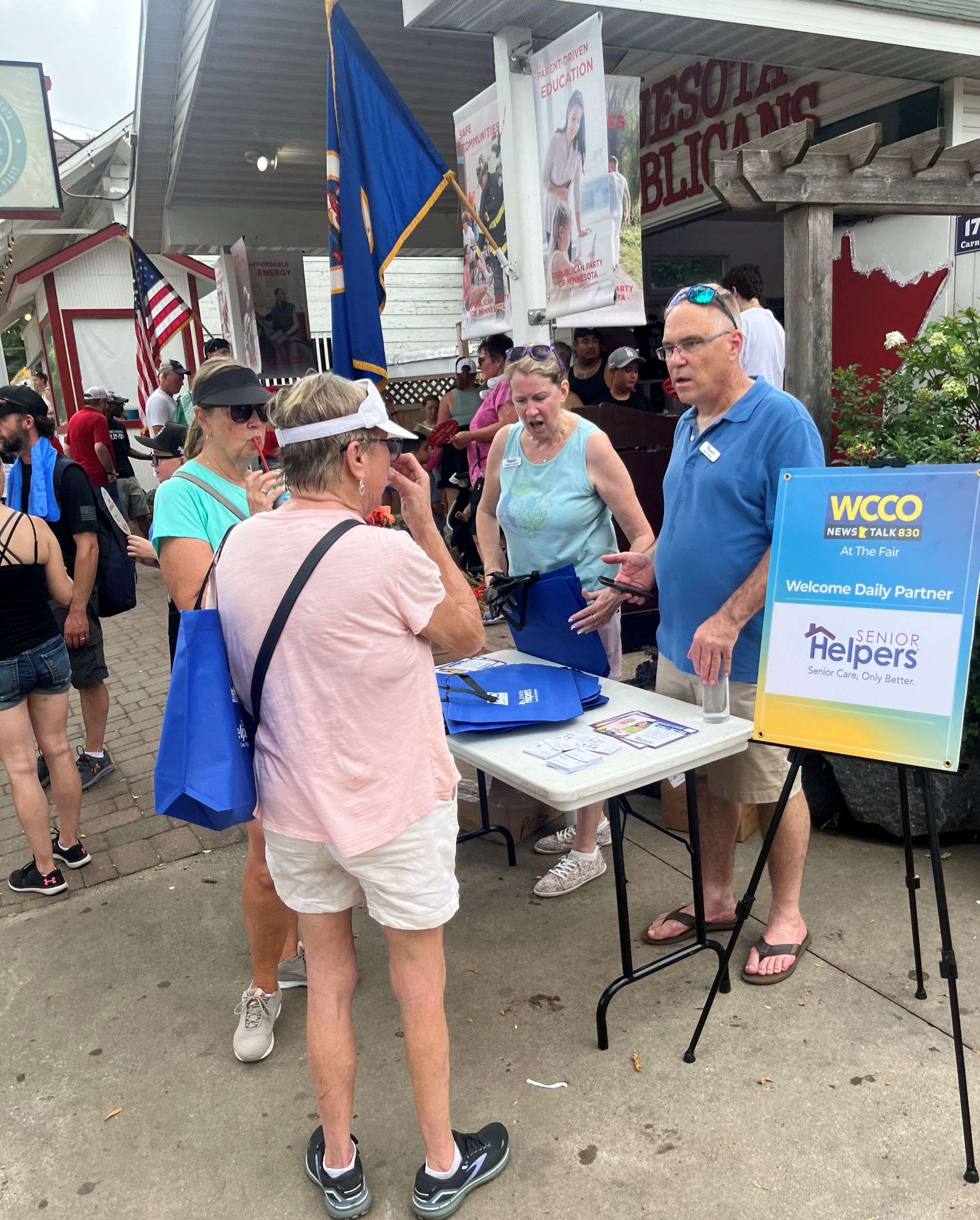 Steve Smela and Carrie Carlson, Senior Helpers of Burnsville & South Metro hand out tote bags and postcards to seniors at the MN State Fair.